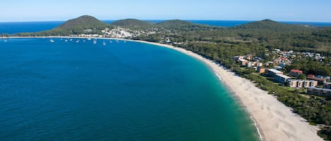 Une vue aérienne d’une zone côtière avec une plage, des bateaux et des bâtiments.
