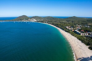 An aerial view of a coastal area with a beach, boats, and buildings.