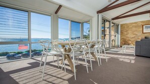Ein geräumiger Balkon mit Meerblick, ausgestattet mit weißen Stühlen und einem Holztisch.