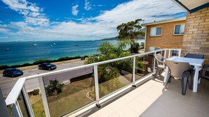 Ein Balkon mit Meerblick, einem Tisch, Stühlen und einem geparkten Auto.