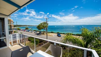 A balcony with a view of a beach and the sea.