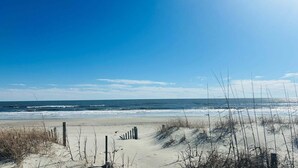 A beach with sand dunes, a wooden fence, and the ocean. - Discover Hidden Treasure: a cozy 2-bedroom oceanfront stay at Holden Beach! (Holden Beach)