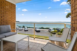 Un balcon avec vue sur un parking et la mer.