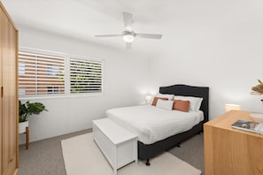 A bedroom with a bed, bedside table, bench, ceiling fan, window with blinds, and a potted plant. - South Pacific Shoal Bay Escape with Water Views (Shoal Bay)