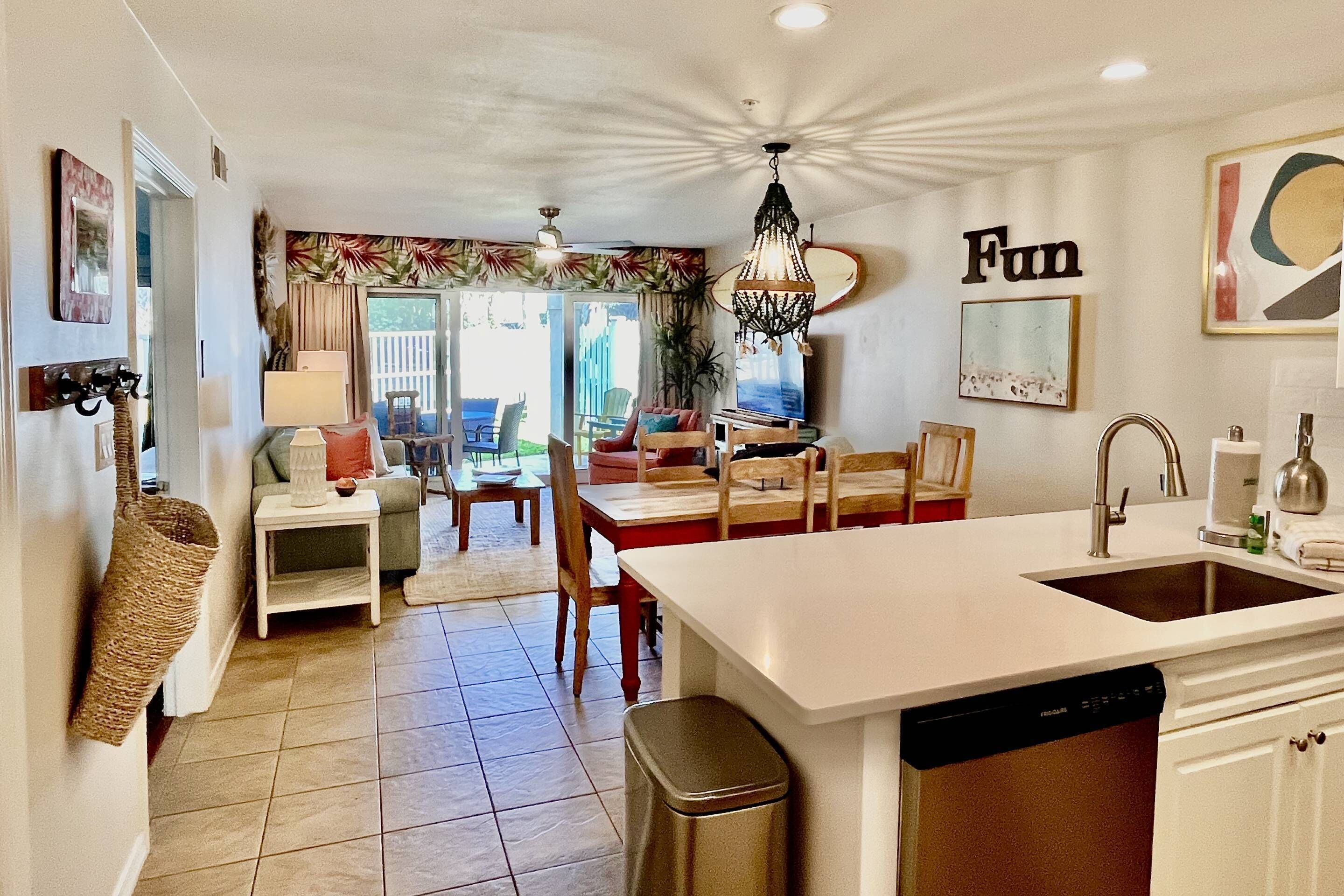 A modern kitchen with a central island, a dining area with a table and chairs, and a view of the outdoors.