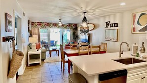 A modern kitchen with a central island, a dining area with a table and chairs, and a view of the outdoors. - PET FRIENDLY, Private Beach Access, Beach Setup, Pools, HotTub, Tennis/Pickleball, Maravilla 1st Fl (Miramar Beach)