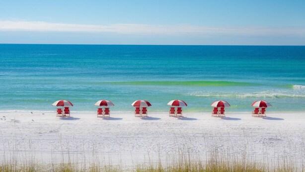 A beach with six red and white beach umbrellas and chairs aligned in a row. - PET FRIENDLY, Private Beach Access, Beach Setup, Pools, HotTub, Tennis/Pickleball, Maravilla 1st Fl (Miramar Beach)