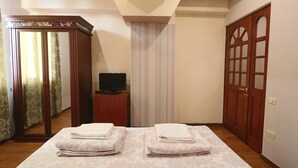 Une chambre d’hôtel avec un lit, un téléviseur posé sur une petite table, une armoire et des rideaux.