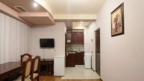 Un espace de vie compact comprenant un coin repas, une kitchenette et un téléviseur fixé au mur.