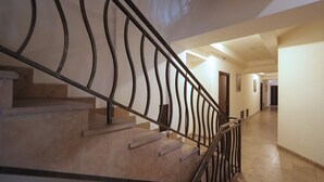 Un escalier avec une rampe métallique menant à un palier.