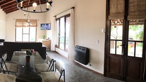 A spacious kitchen with a dining area, large windows, and a TV mounted on the wall.
