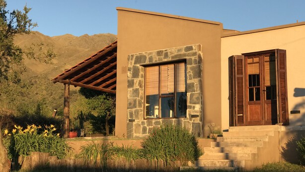 A modern house with a stone facade, a wooden pergola, and a front door.