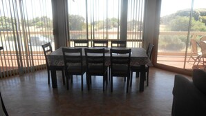 A dining area with a table and chairs, large windows with blinds, and a view of the outdoors. - Hardwicke Espy   close to beach (Hardwicke Bay)