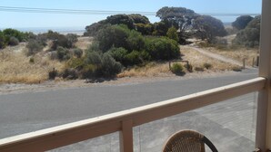 A view from a window overlooking a road with a wooden fence and sparse vegetation. - Hardwicke Espy   close to beach (Hardwicke Bay)