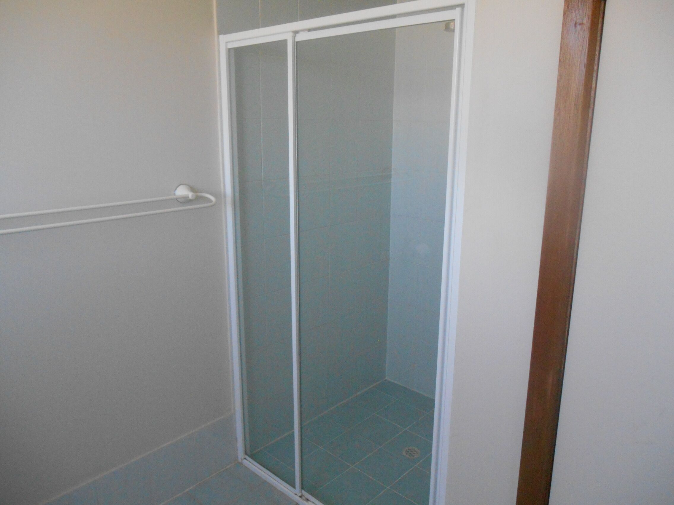 Un baño con cabina de ducha de vidrio, paredes blancas y suelo de baldosas.
