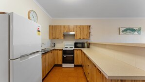 Una cocina compacta equipada con refrigerador, estufa, microondas y gabinetes de madera.
