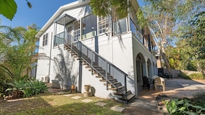 Una casa de dos pisos con escaleras, mobiliario exterior y un jardín.