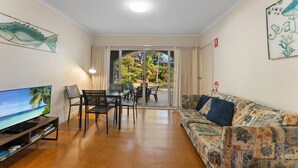 A living room with a television, seating, and a view through a glass door to an outdoor area. - Shoal Bay Avenue 2 close to Beach (Shoal Bay)