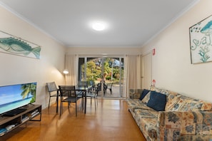 A living room with a television, seating, and a view through a glass door to an outdoor area. - Shoal Bay Avenue 2 close to Beach (Shoal Bay)