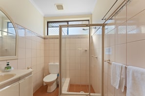 Een badkamer met douche, toilet en wastafel.