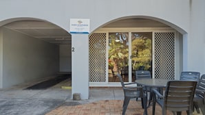 A covered outdoor seating area with a table and chairs, a sign for Port Stephens Holiday Rental, and a number '2' on the wall. - Shoal Bay Avenue 2 close to Beach (Shoal Bay)