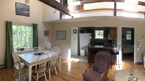 A spacious living area with a dining table, chairs, a sofa, and a kitchen in the background.