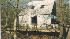 A cabin with a wooden deck, a front door, and a small porch area.