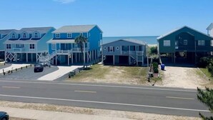 A row of beach houses with a sandy driveway and a clear blue sky. - Libby's Lookout: Spacious 4-bedroom retreat near the beach in Holden Beach, NC. (Holden Beach)