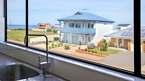 A modern kitchen with a large window overlooking a residential area and a beach. - Blue Door Retreat  - Excellent Off Peak Special!  Nightly rates reduced!! (Edithburgh)