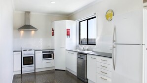 A modern kitchen with white cabinetry, a stainless steel range hood, a dishwasher, and a refrigerator. - Blue Door Retreat  - Excellent Off Peak Special!  Nightly rates reduced!! (Edithburgh)