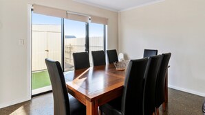 A conference room with a wooden table and black chairs, large windows with blinds, and a view of a fenced area. - Blue Door Retreat  - Excellent Off Peak Special!  Nightly rates reduced!! (Edithburgh)