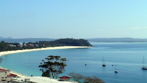 Une vue sur la côte, avec une plage de sable, une mer bleue et limpide, et plusieurs bateaux.