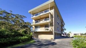 Un immeuble résidentiel à plusieurs étages, doté de balcons, d’un toit plat et surplombant un ciel dégagé.