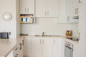 Eine moderne Küche mit weißen Schränken, einer Mikrowelle, einem Toaster und einem Spülbecken.