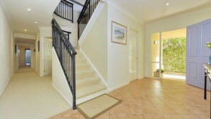 Un pasillo espacioso con escalera alfombrada, una puerta que da a un jardín y vistas al exterior.