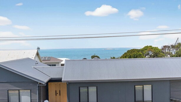 A residential building with a view of the sea and a distant island.