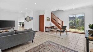 A spacious living room with a grey sofa, a TV, and a staircase leading to another level.