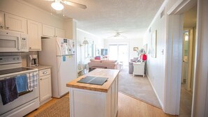 A modern kitchen with white cabinetry, a central island, and a ceiling fan. - Relax and unwind in Feelin' Beachy (Holden Beach)