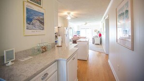 A kitchen with granite countertops, white cabinetry, and a central island. There are framed pictures on the walls and a ceiling fan. - Relax and unwind in Feelin' Beachy (Holden Beach)