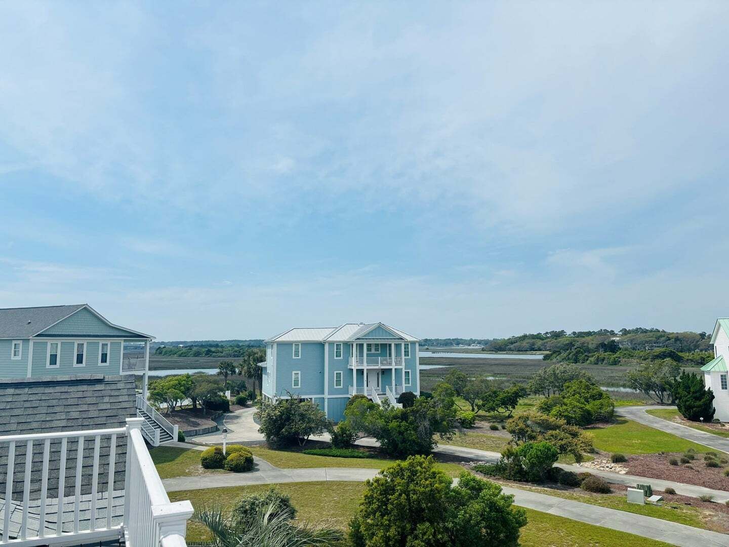 A residential area with houses, a clear sky, and a body of water in the background.