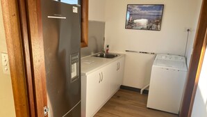 Kompakti keittiö, jossa on jääkaappi, pesuallas ja pyykinpesukone.