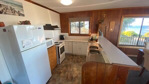 Kompakti keittiö, jossa on jääkaappi, liesi, mikroaaltouuni ja pesuallas. Siellä on myös ikkuna, josta on näkymä ulos.