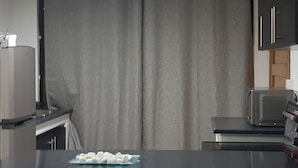 Una cocina con encimera negra, un microondas y un tostador. Hay un recipiente de vidrio con comida en la encimera.