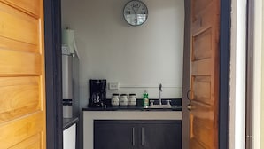 Una cocina estrecha con una cafetera, frascos y un reloj en la pared.