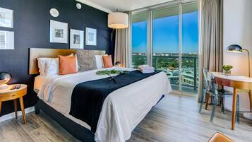 Ein modernes Hotelzimmer mit einem großen Bett, einem Schreibtisch und Blick auf die Stadt.