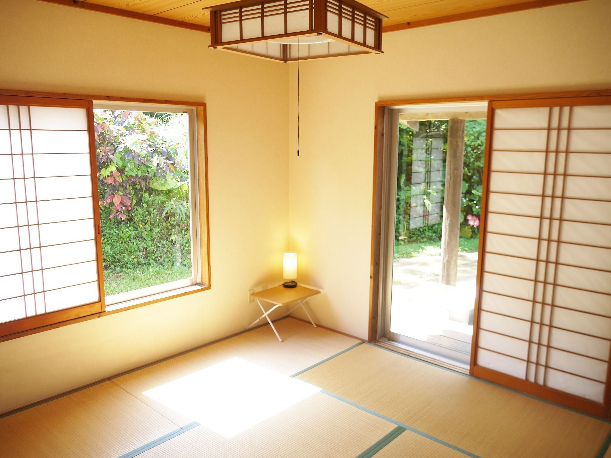 Een traditionele Japanse kamer met tatami vloeren, schuifdeuren en een tafeltje met een lamp.