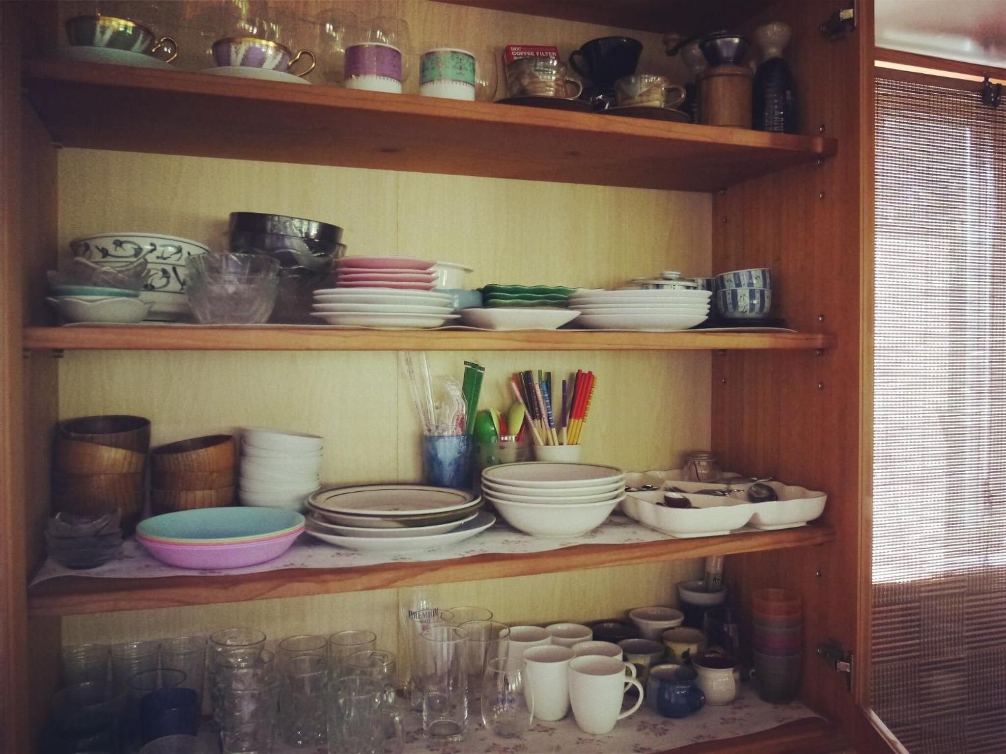 Een houten plankenwand met diverse serviesdelen, bekers en bestek.