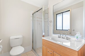 Een badkamer met toilet, douchecabine en wastafel met spiegel erboven.