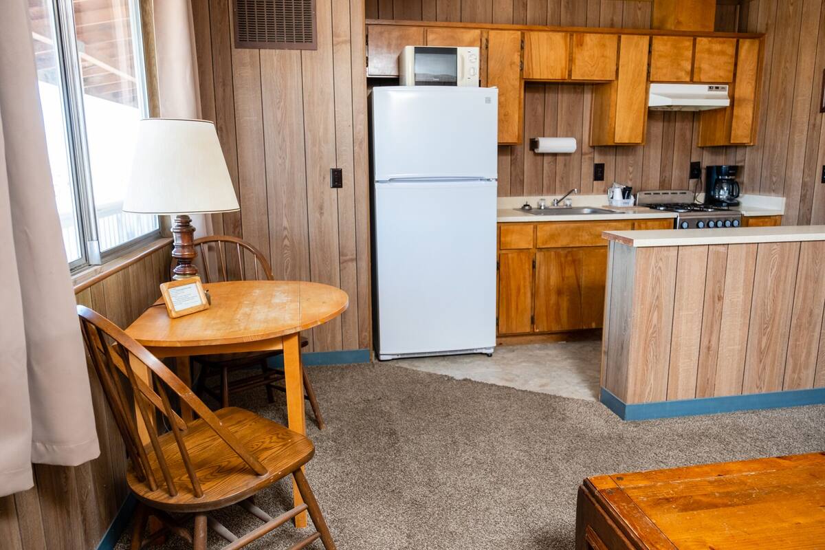 A compact kitchen with wooden cabinets, a refrigerator, a microwave, a sink, and a stove.