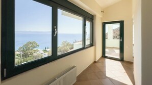 A hallway with large windows offering a view of the sea and a building. - villa with great seaview (Schinias)